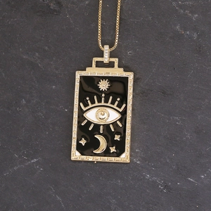 Detail of gold evil eye square pendant with black enamel, moon and star engraving
