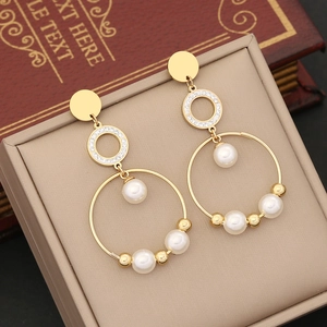 Macro shot of gold-plated double hoop earrings with white pearls and sparkling rhinestones