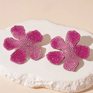 Macro shot of sparkling rose pink gradient flower earrings with pavé rhinestones on stone