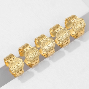 Detail of square embossed gold letter rings S R P T Q on white geometric stands