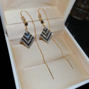 Détails macro de boucles d'oreilles dorées à pampilles avec losanges sertis de diamants