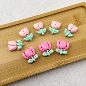 Close-up of glossy resin tulip flower charms in pink on a wooden tray for DIY crafts