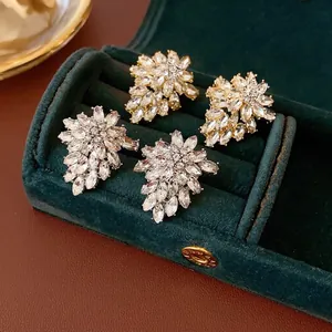 Elegant floral stud earrings in gold and silver set in a green velvet jewelry box