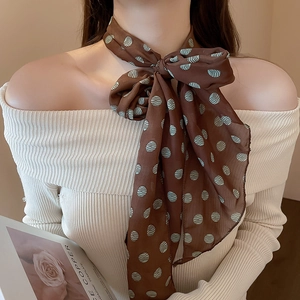 Detail of coffee brown silk scarf with blue polka dots tied on model neck