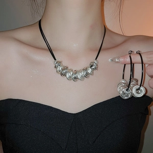 Detail of silver twisted circle pendant on black leather cord with matching hoop earrings