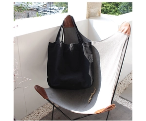 Detailed view of black canvas tote bag on an armchair in a natural outdoor terrace setting