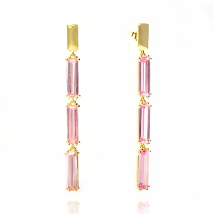Macro detail of gold tassel earrings featuring three-tiered rectangular pink gemstones
