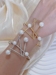 Detail view of elegant irregular geometric pearl bracelets in polished gold and silver