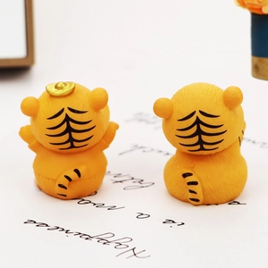 Macro shot of two cute orange resin tiger figurines with lucky golden ingots on top