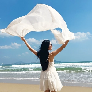 White linen cotton shawl scarf blowing in the wind on a sunny beach background