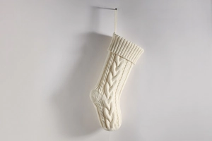 Close-up of cream white cable knit Christmas stocking hanging on a clean white background