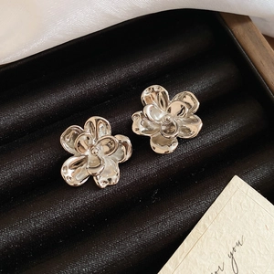 Detailed macro view of silver flower stud earrings on black velvet and white silk fabric