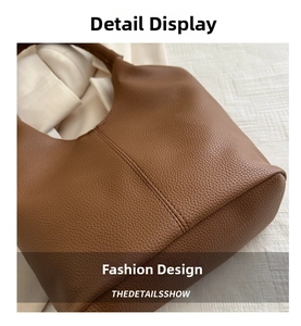 Close-up of brown lychee grain leather texture and reinforced stitching on the bucket bag