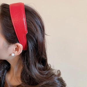 Detail showing the red leather headband texture and stitching on a brunette model
