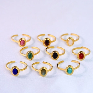 Detailed flat lay of nine gold adjustable rings with assorted colorful oval gemstones