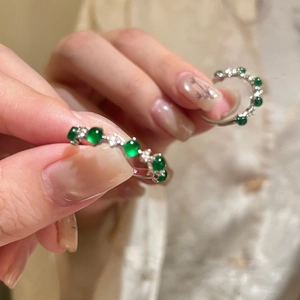 Detail of silver stud earrings featuring green zircon stones in a claw setting