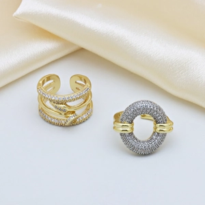 Due anelli aperti placcati in oro 18k con design traforato e zirconi su sfondo di seta