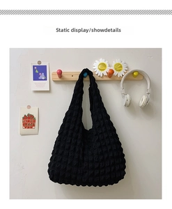 Detail of black popcorn texture shoulder bag with soft elastic pleated fabric surface