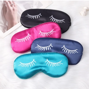 Close-up of four colorful silk sleep masks with eyelash prints on white plush surface