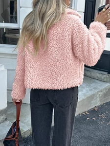 Rear view of an elegant pink faux fur teddy jacket for women in a street style setting