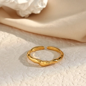 Polished gold irregular bamboo wave open ring on a textured neutral fabric background