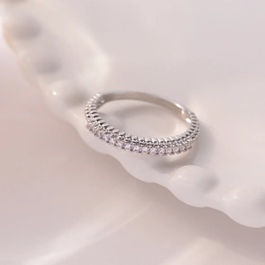 Minimalist silver full eternity ring with clear zircons on a white ceramic tray