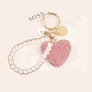 Dettaglio portachiavi a cuore con strass rosa, cinturino di perle e anello dorato