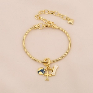 Macro shot of gold-plated snake chain bracelet with globe and airplane travel charms
