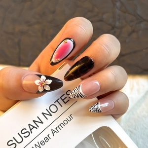 Detail of almond press-on nails featuring 3D white flowers and zebra French tip designs
