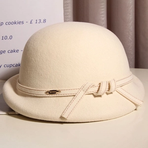Detailed macro view of the elegant beige wool felt cloche hat with a bow and metal badge