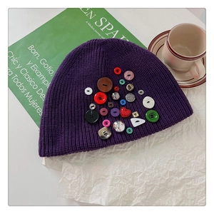 Detail of creative colorful buttons on a dark purple knitted beanie hat for winter