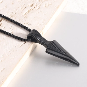 Arrowhead pendant necklace in black stainless steel on textured stone background