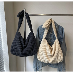 Detail of corduroy tote bags with knotted straps in black and beige finishes