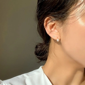 Elegant gold pearl drop earrings with four-prong zircon stud shown on a model profile