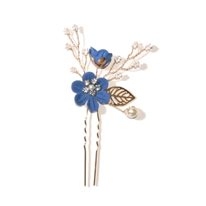 Detailed close-up of blue fabric flower hair pin with golden leaves and white pearls