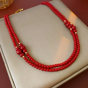 Dettaglio ravvicinato della collana a doppio strato con perline rosse e accenti dorati