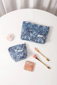Flat lay of vintage blue paisley jacquard cosmetic bags with metallic floral zippers