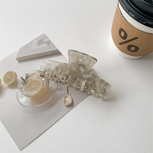 Flat lay of white shell texture acetate hair claw clip with lifestyle magazine and coffee