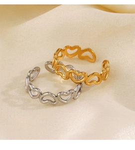 Detail of hollow heart rings in gold and silver finish on soft satin fabric background