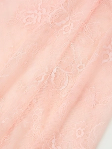Close-up of soft pink lace fabric featuring intricate floral embroidery and sheer mesh