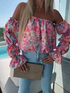 Dettaglio della camicetta a fiori con spalle scoperte, rose rosa e polsini a balze