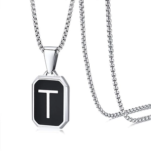 Detail view of a square black pendant with a silver letter T on a stainless steel chain