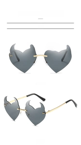 Detail display of devil heart-shaped rimless sunglasses in grey and gold metal frame