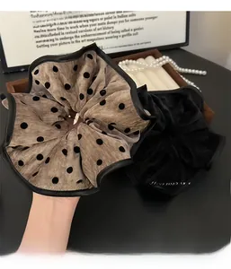 Close-up of oversized polka dot fabric and black velvet scrunchies with pearl accessories