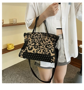 Detail of leopard print canvas handbag with black faux leather base and metal studs