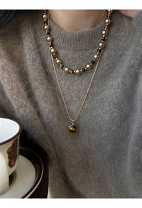 Détail d'un collier multicouche plaqué or avec perles d'oeil de tigre et pendentif rond