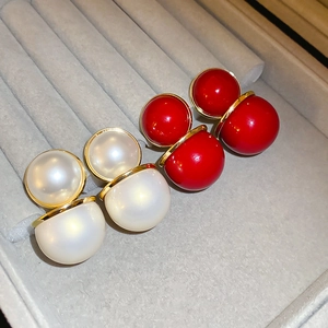 Vue macro de boucles d'oreilles perles double face rouges et blanches sur plateau velours