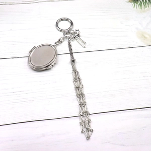 Silver locket keychain with star charm and long geometric tassels on wooden background
