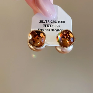 Detail of 18K gold-plated earring with champagne crystal and round pearl in macro view