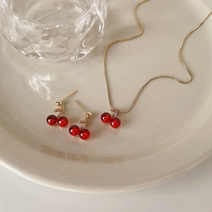 Primo piano dettagliato di set gioielli ciliegia con perline rosse e zirconi su piatto